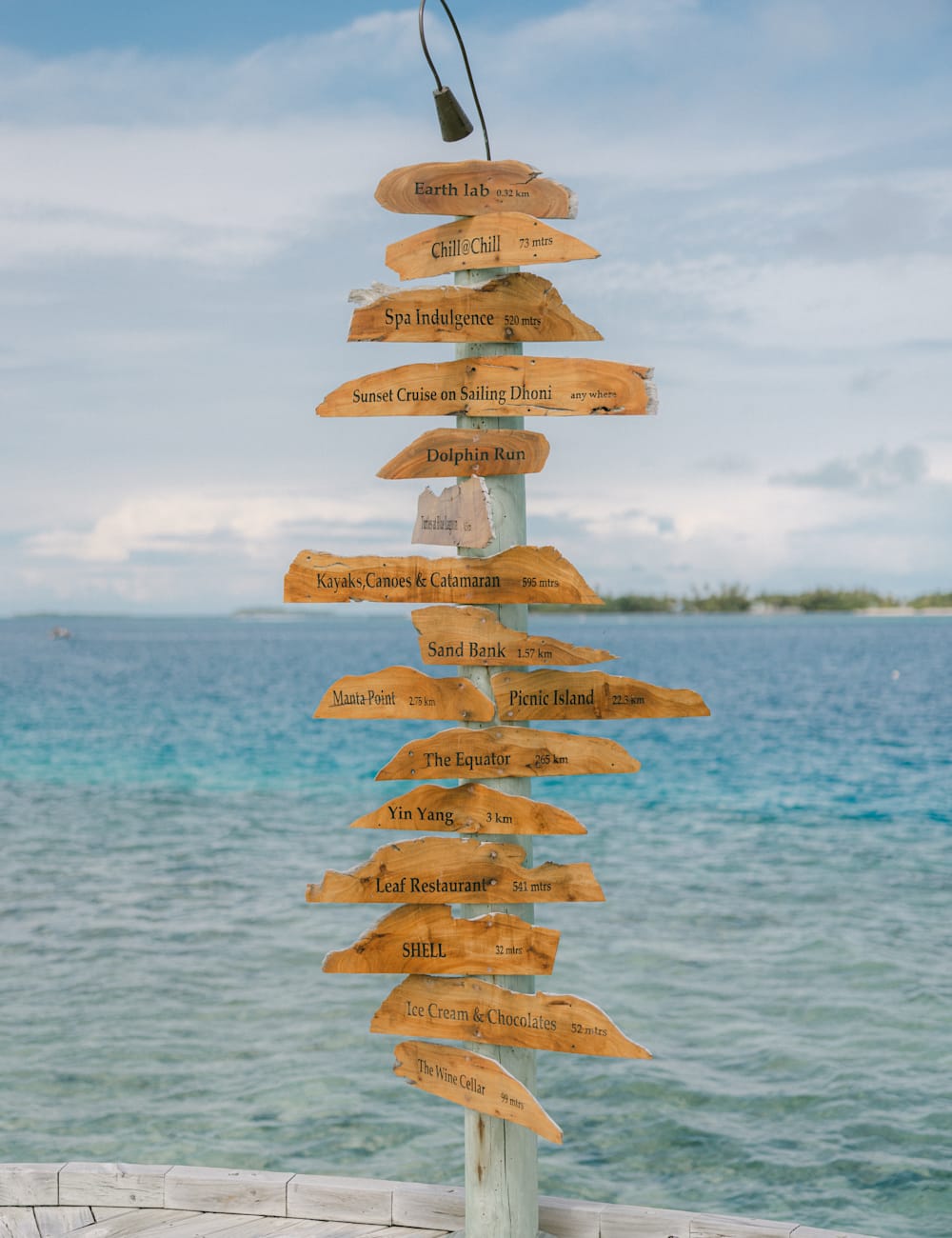 Signposts in front of the sea at Six Senses Laamu, by Holly Clark for Mr & Mrs Smith
