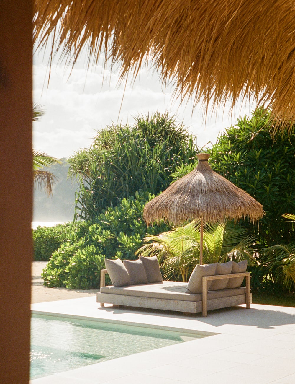 Sun lounger under a thatched parasol at the Sanubari hotel, Sumba
