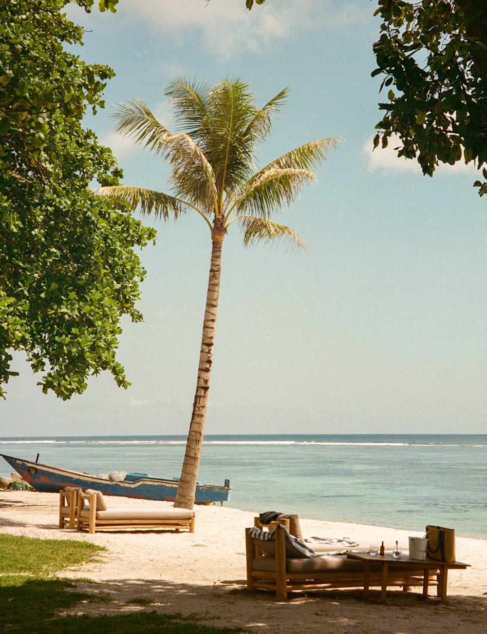 Palm tree, fishing boat and beach loungers at Cap Karoso, Sumba, by Hannah Dace for Mr & Mrs Smith