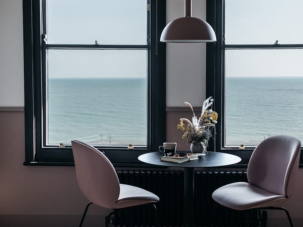 Table and chairs with flowers and a sea view at Port Hotel, Eastbourne