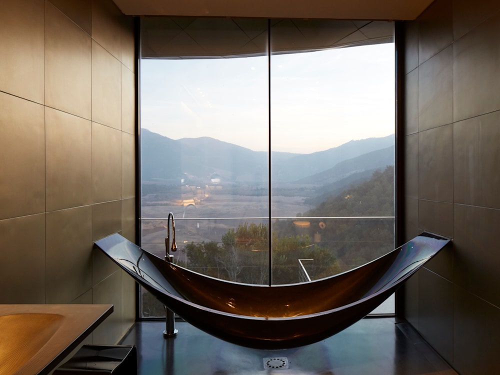 The curved floating bath is in front of floor to ceiling windows looking out onto the mountains