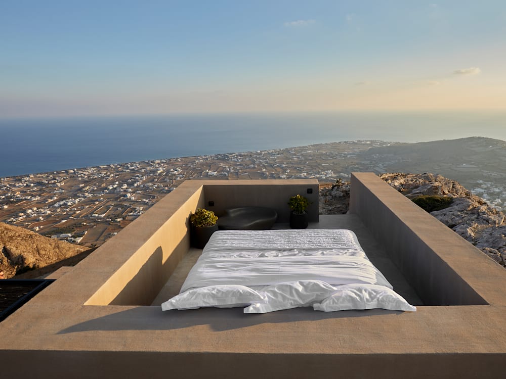 Rooftop bed over looking the Caldera. The rolling hills fall away and the dark blue sea stretches out into the distance
