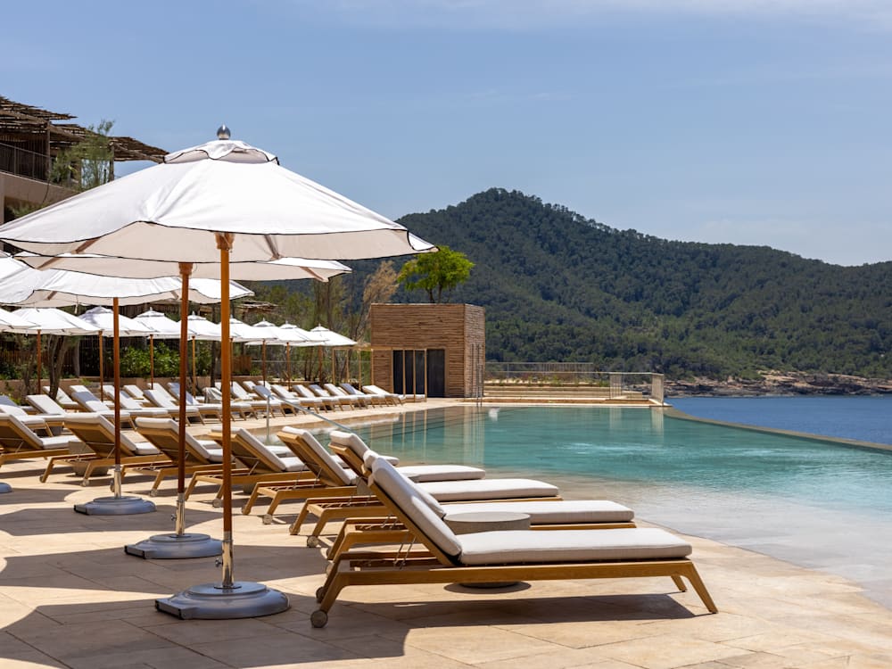 Sun beds and parasols on the edge of an infinity pool overlooking the ocean