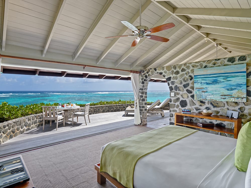 High ceilinged light and air bedroom looking out to the sun drenched terrace and aquamarine blue sea