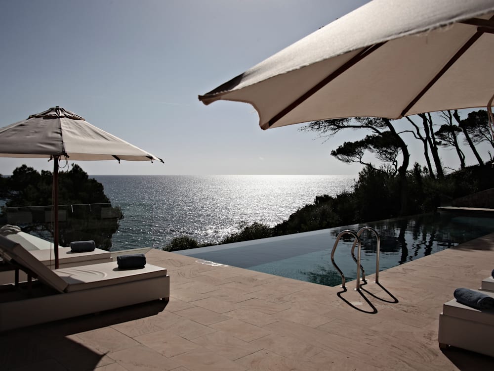 Infinity pool on the edge of a cliff over looking the sea with sun loungers and parasols 