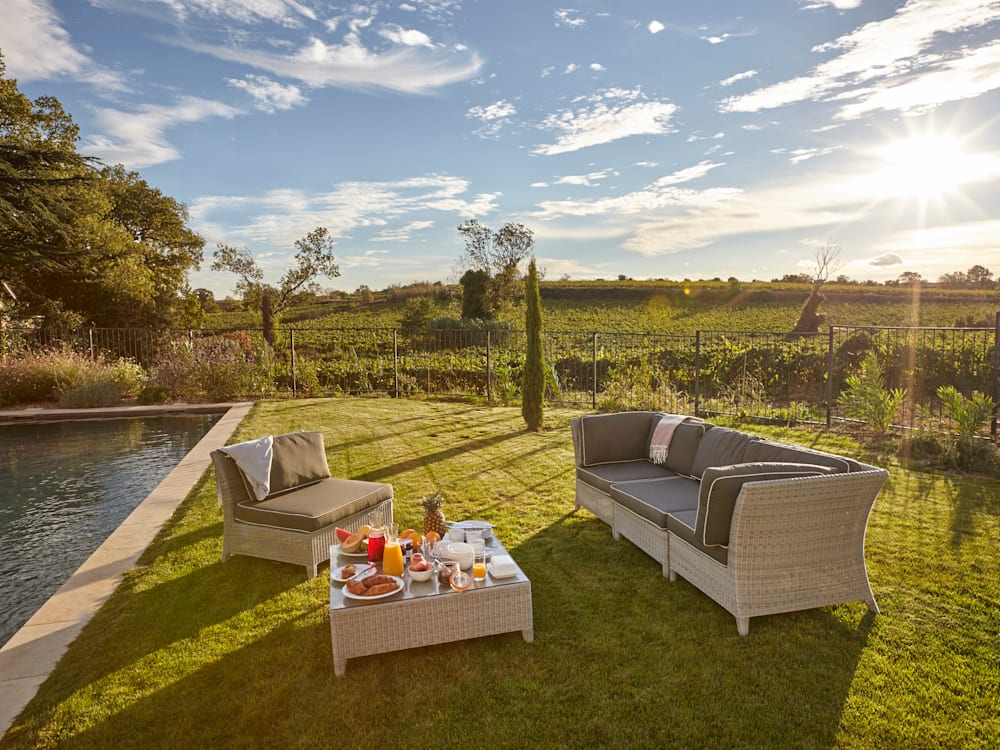 Outdoor sofa and picnic by the swimming pool in front of the vineyards with the sun setting
