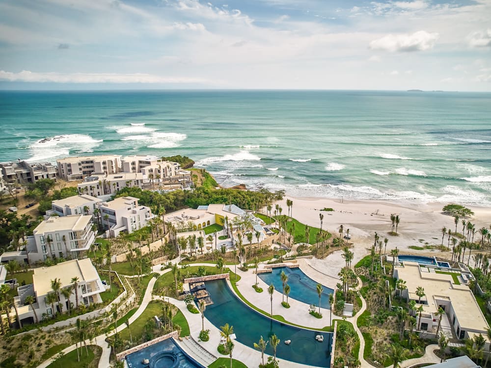 Aerial View of the hotel and swimming pools looking out to the waves rolling in on the white sandy beach