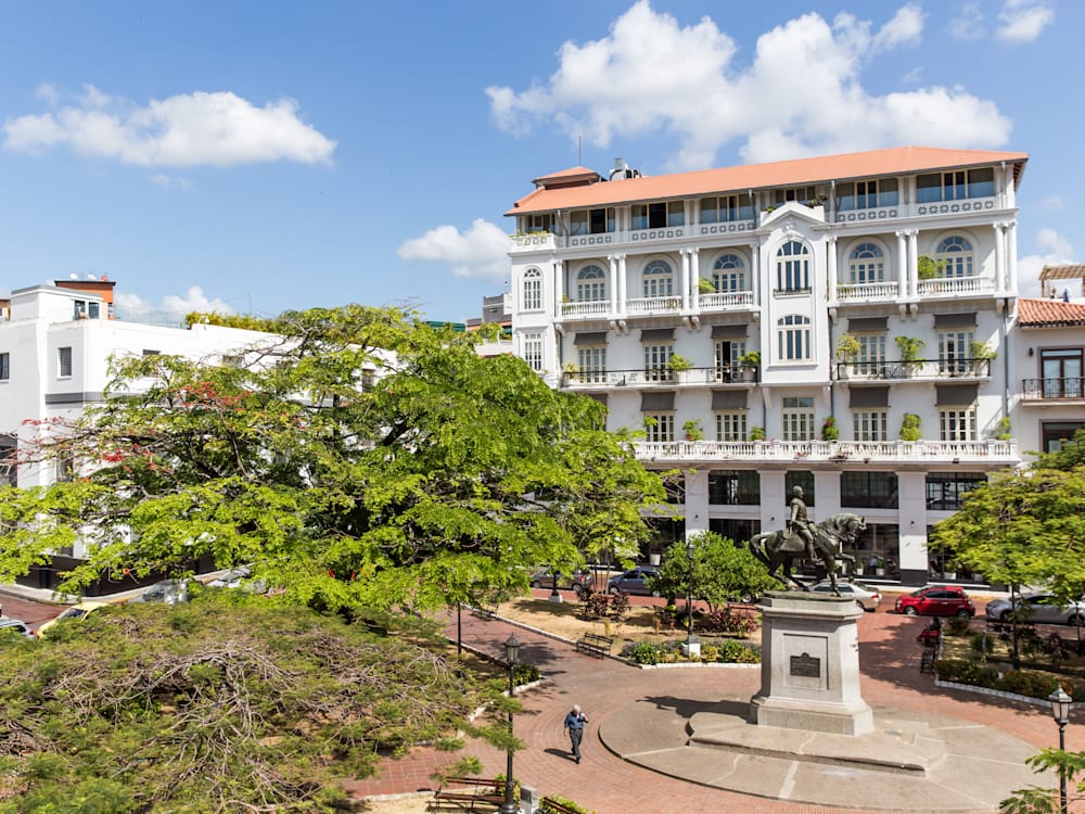 American Trade Hotel exterior with statue and trees in front