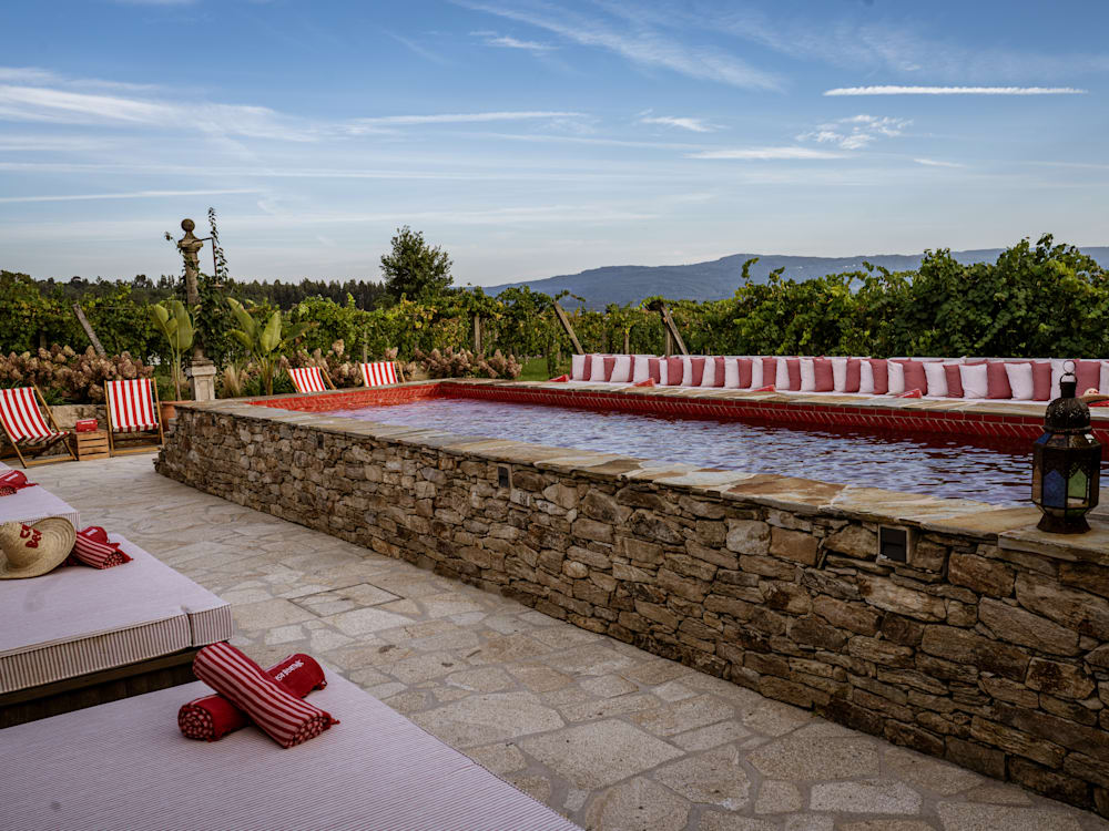 Pool with red tiles and striped towels on cream sun loungers