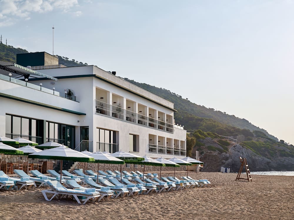 Hotel exterior right on the beach with sun loungers and parasols in the mediterranean sun