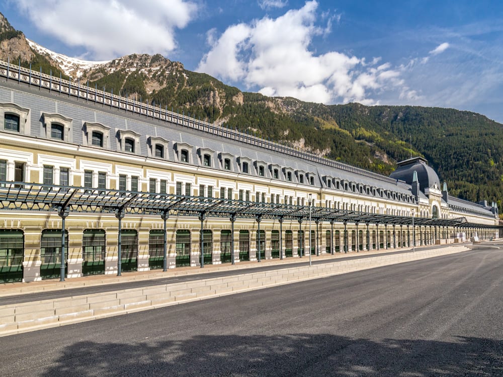 Canfranc Estacion, a train station turned hotel, sits next to a large green mountain