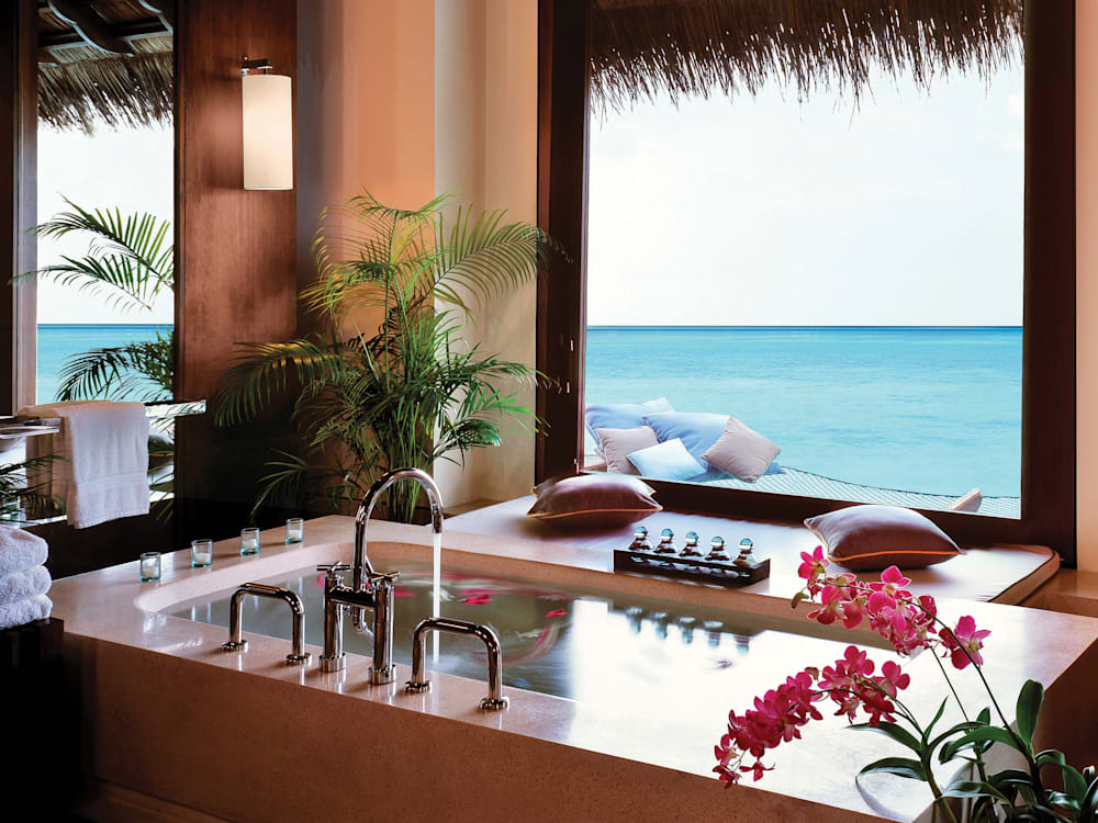 Rectangular bath with the tap running looking out on to the crystal clear blue waters of the ocean.