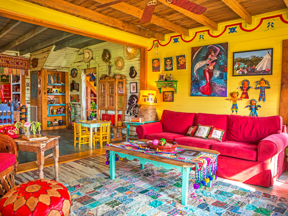 Bright yellow living room with eclectic artwork on the walls, bright red sofas and colourful furniture dominate the room.