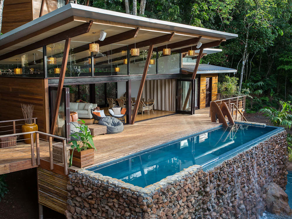 Villa lounge, terrace and swimming pool with water cascading over the edge nestled into the jungle
