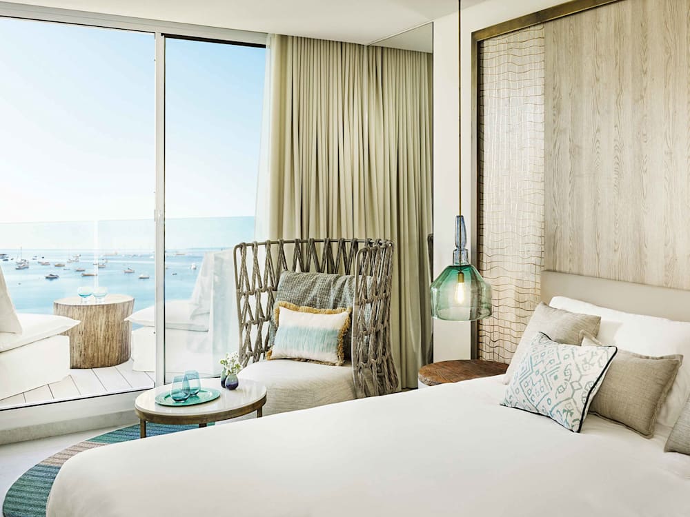 Bedroom looking out to a balcony overlooking the ocean with sailing boats bobbing in the background