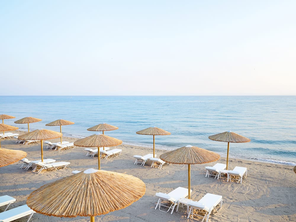 Sun loungers and parasols looking out to sea on the sandy shore