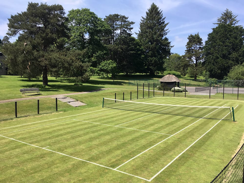 Photograph of the tennis court on green lawns under blue sky