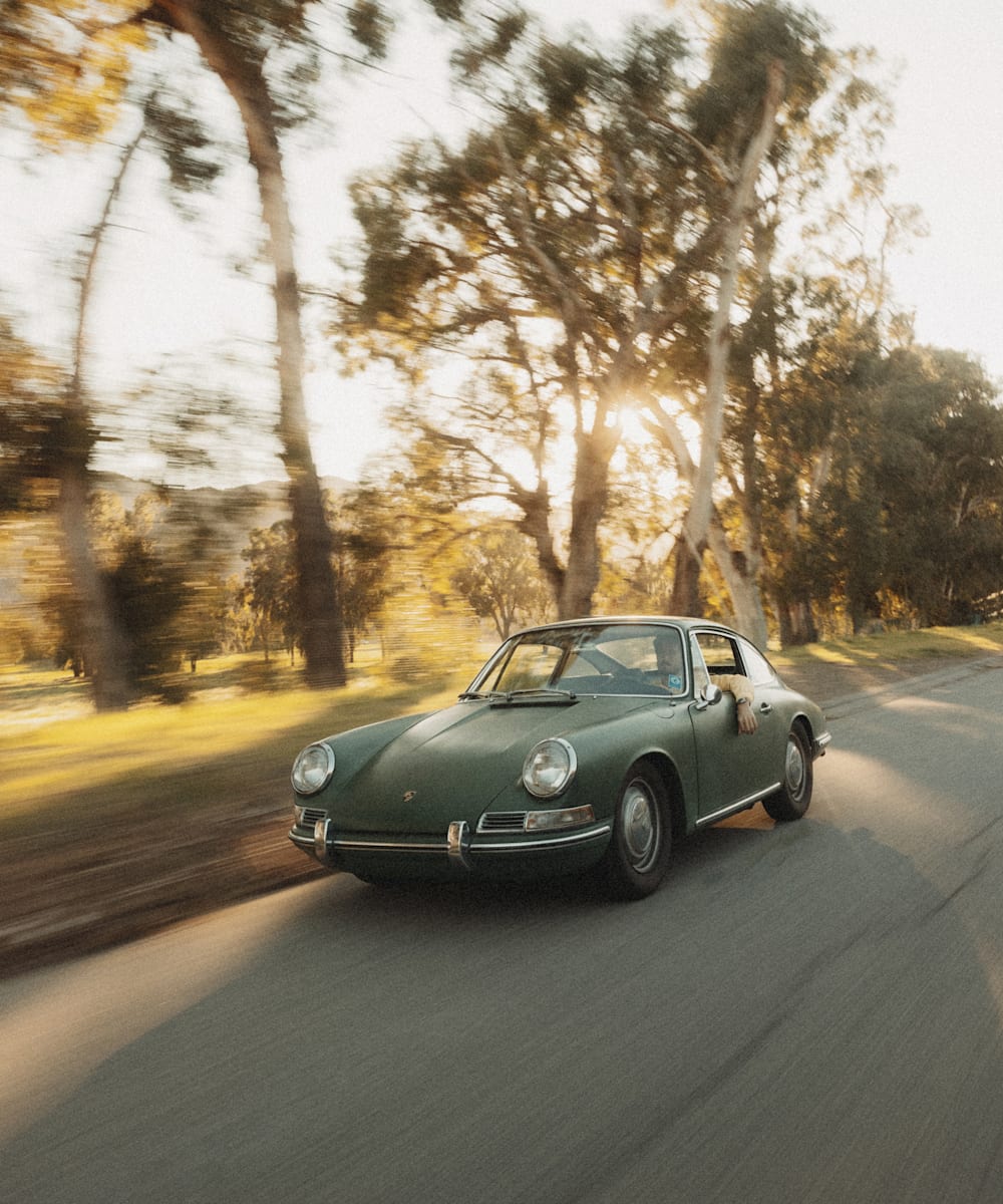 Stuntman Riley Harper driving a vintage Porsche past trees in California