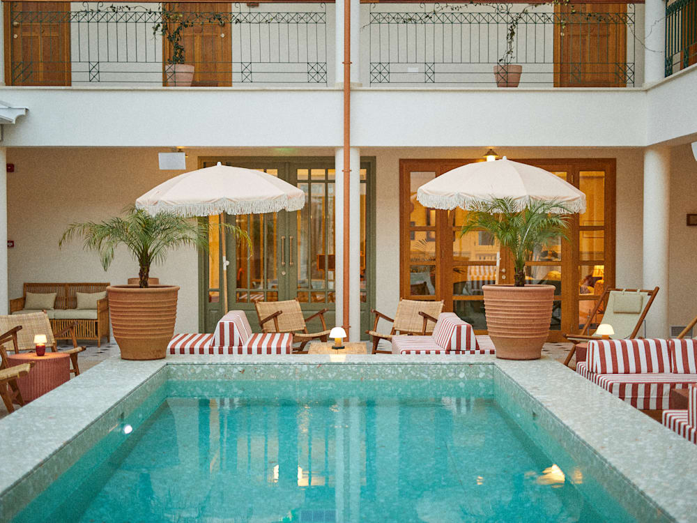 Blue pool with red and white striped loungers and frilly umbrellas